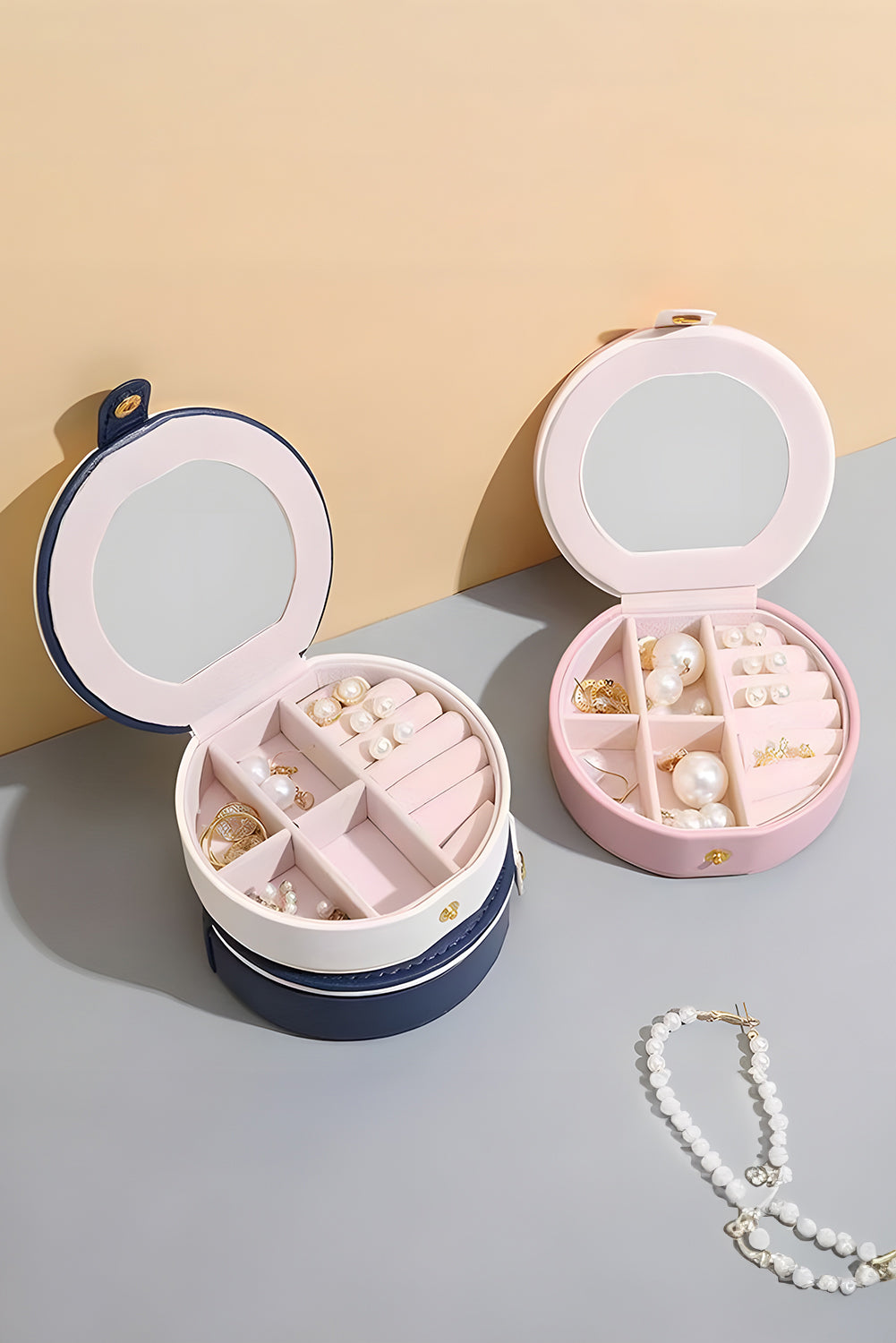 Light pink jewelry organizer case with snap button closure and built-in mirror in compact round shape