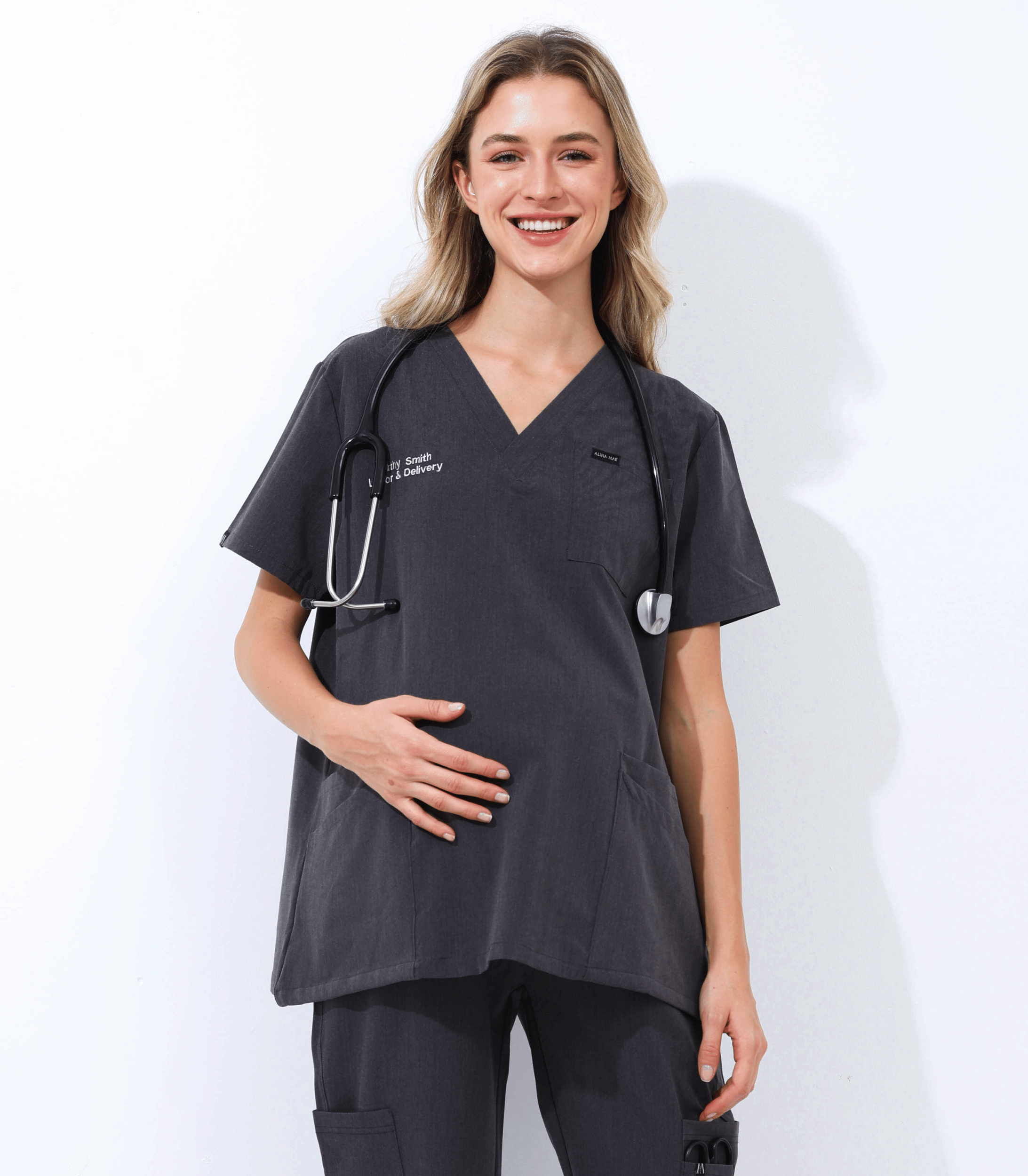 Pregnant medical professional wearing stylish, breathable Mae maternity scrub top for comfort and support