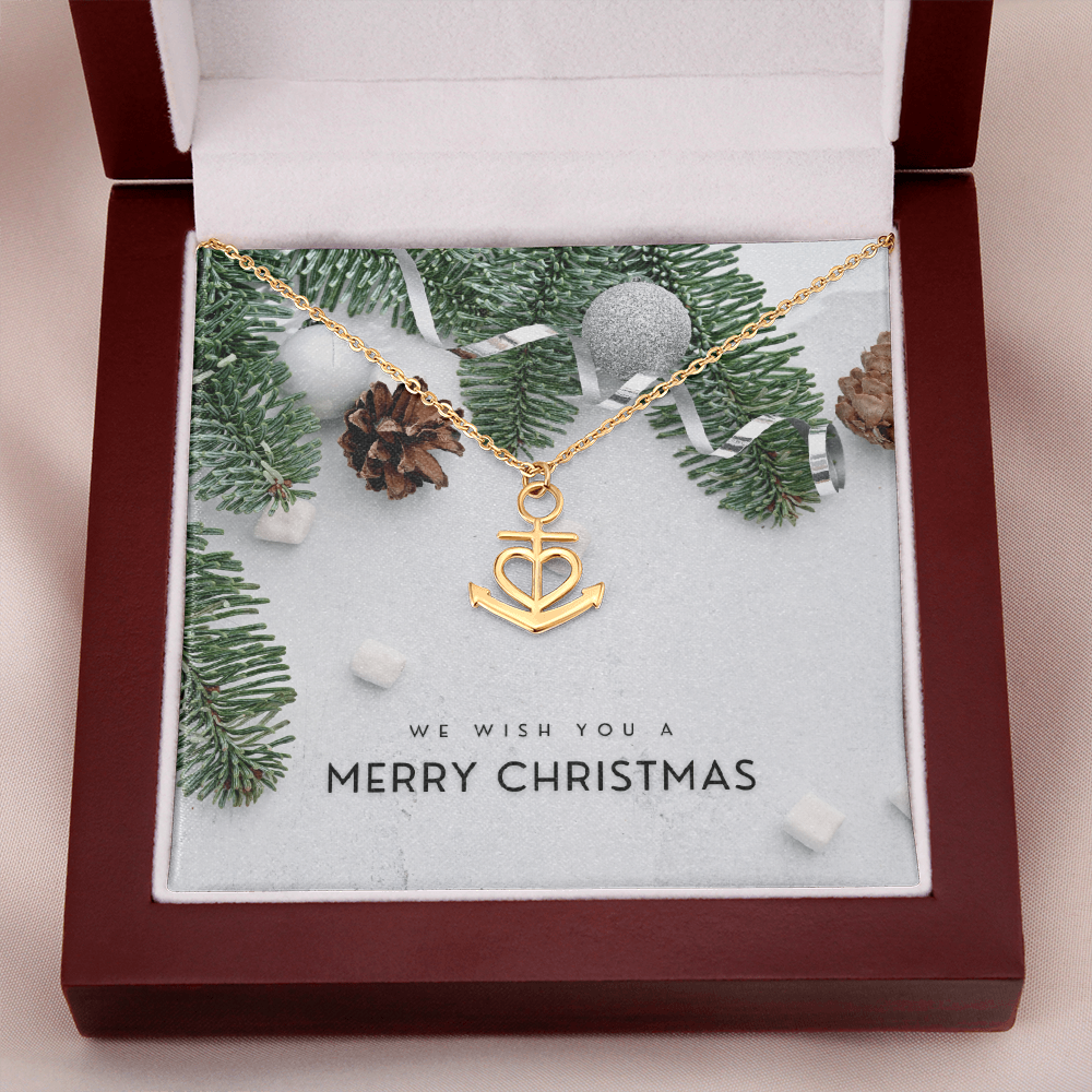 Gold anchor pendant necklace with heart design in Christmas gift box with pine branches and greeting card
