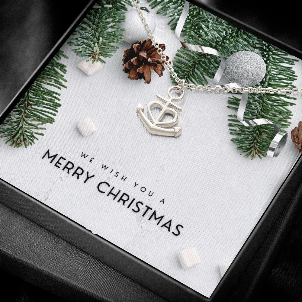 Close-up of polished stainless steel anchor pendant necklace with heart detail on adjustable chain displayed in Christmas gift box with festive decor