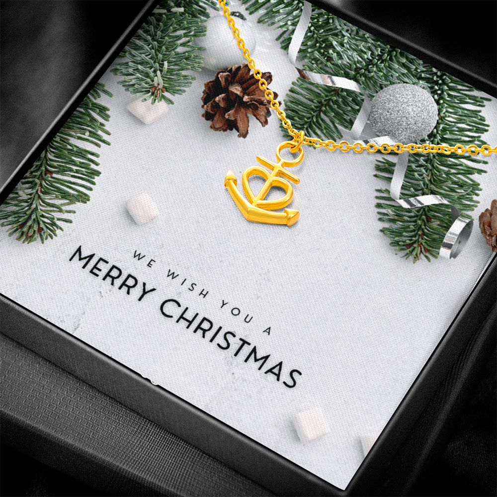 Gold anchor pendant necklace with heart design on a chain in festive gift box with Christmas decor and greeting card