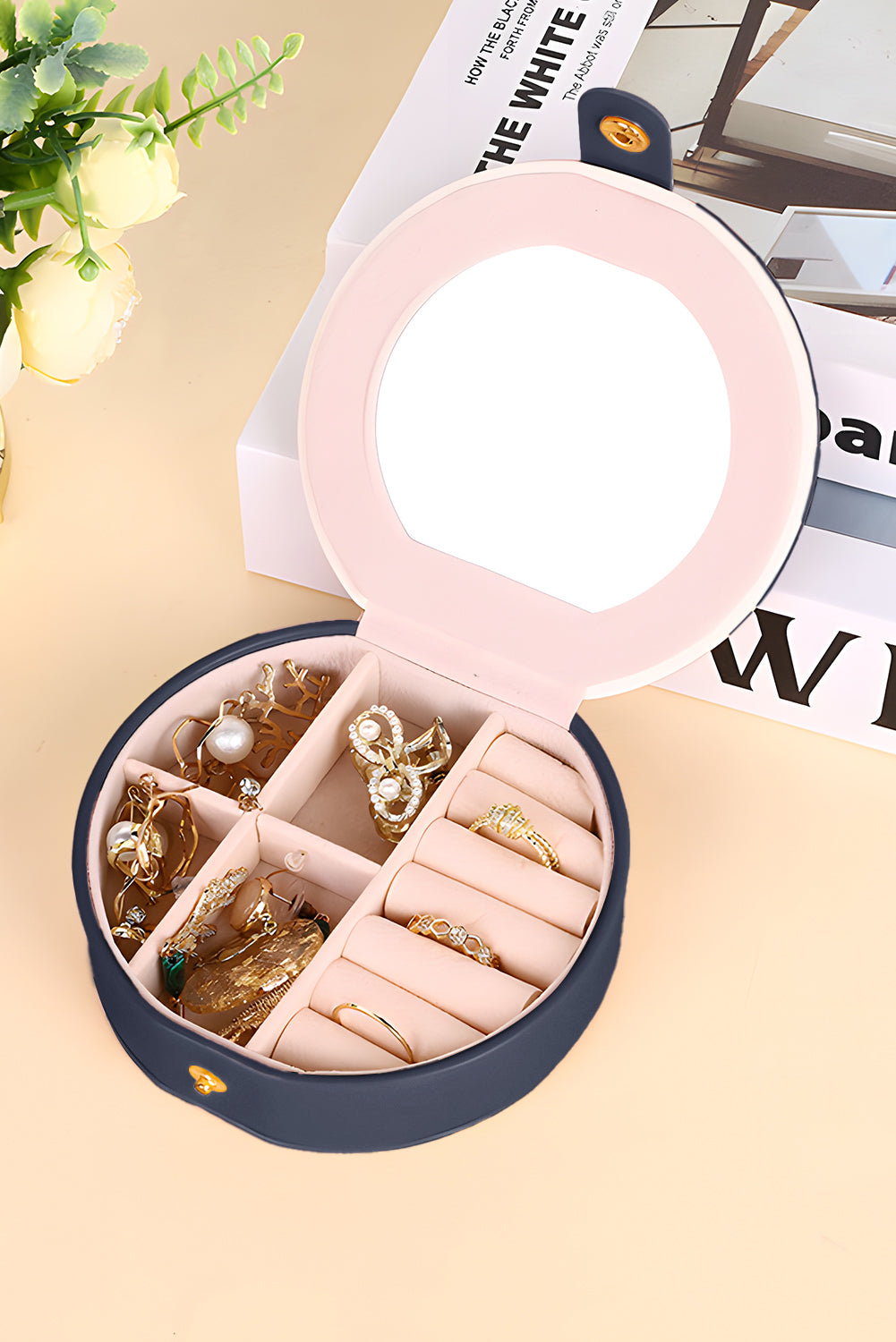 Light pink jewelry organizer case with mirror and snap button closure, compact and round-shaped for easy carrying