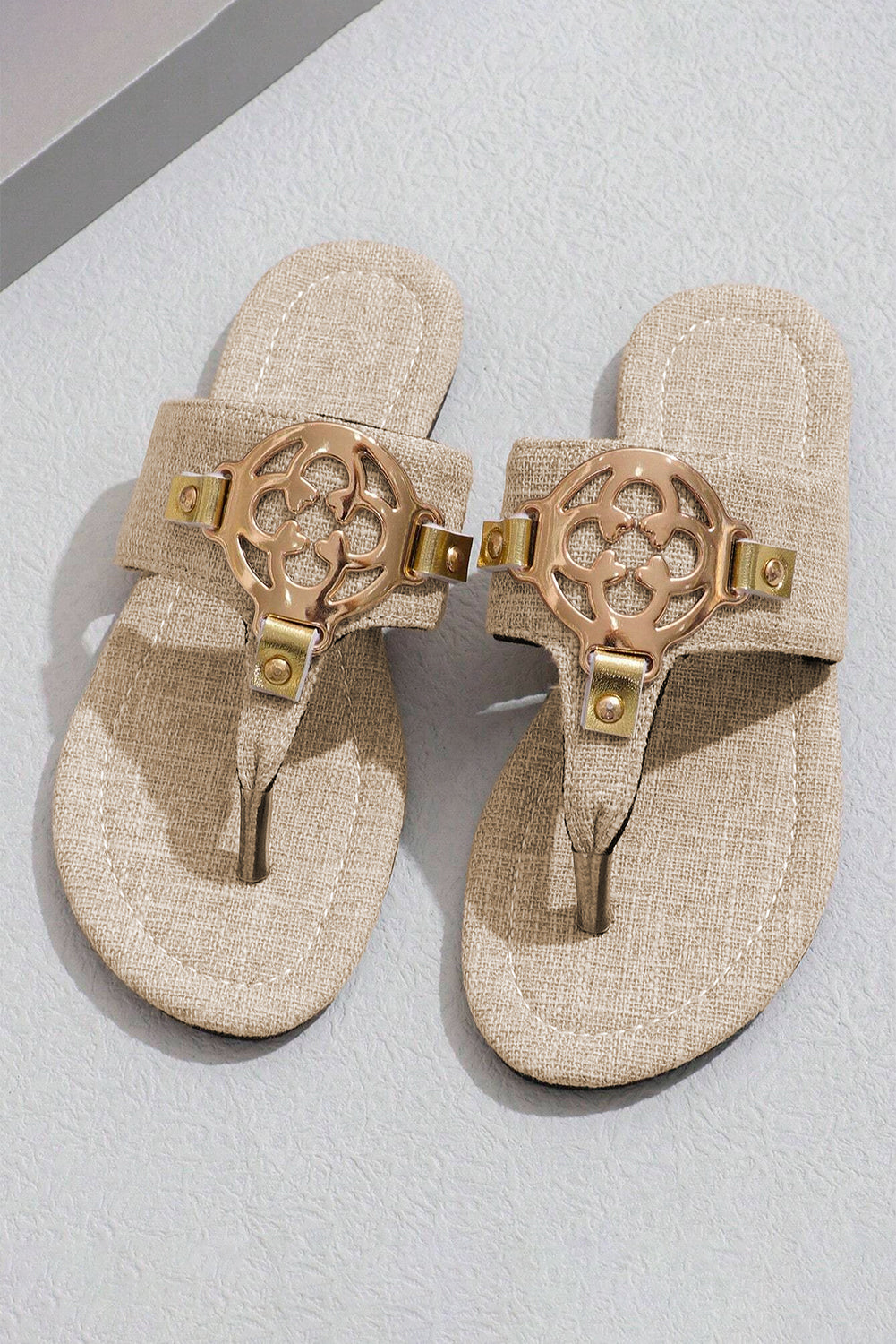 Beige leather thong slippers with stylish metal decor and adjustable strap design